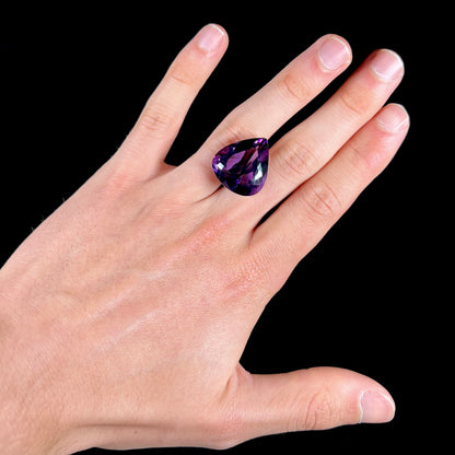 A large, pear shaped amethyst gemstone.  The stone is a dark purple color.