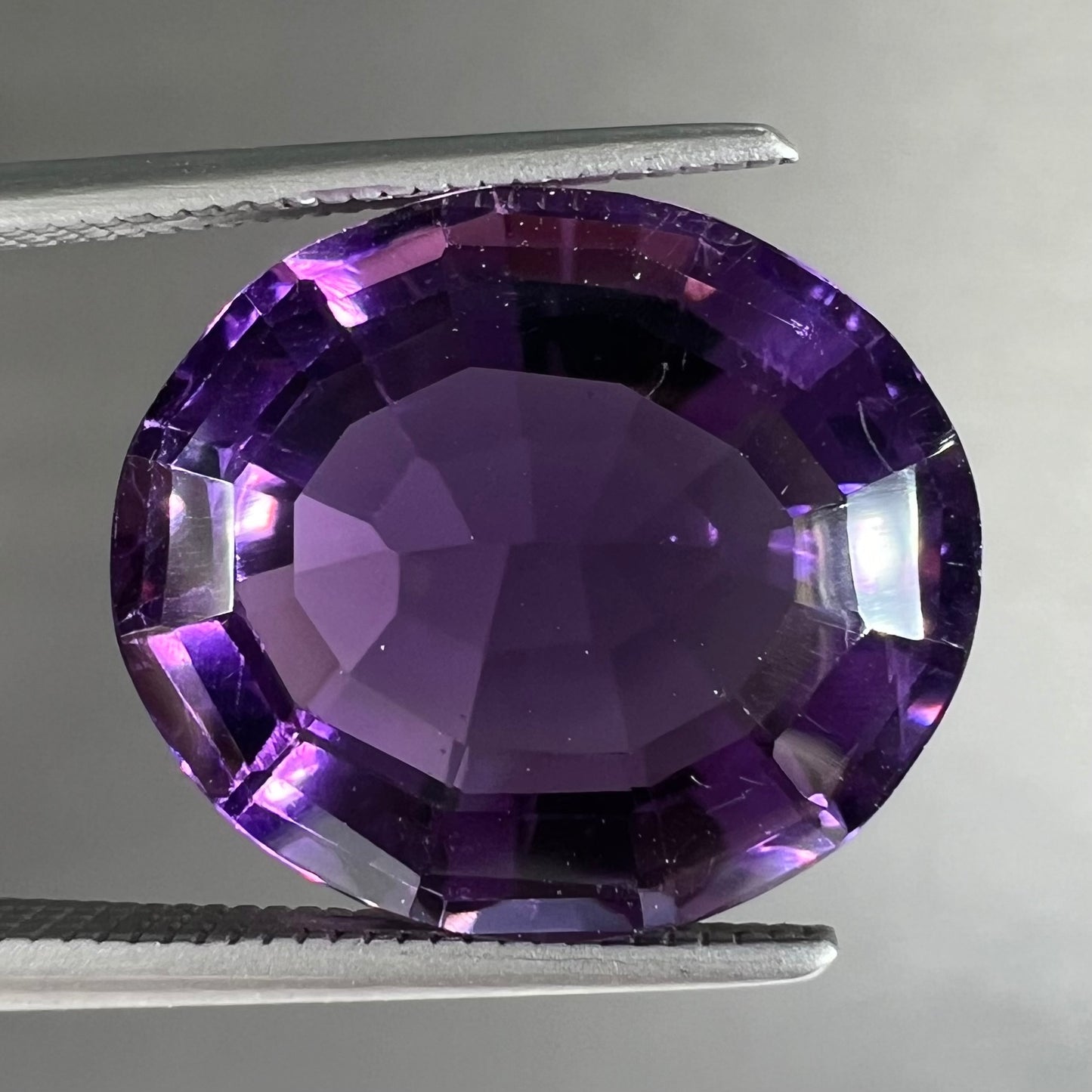 A loose, modified oval cut purple amethyst gemstone.