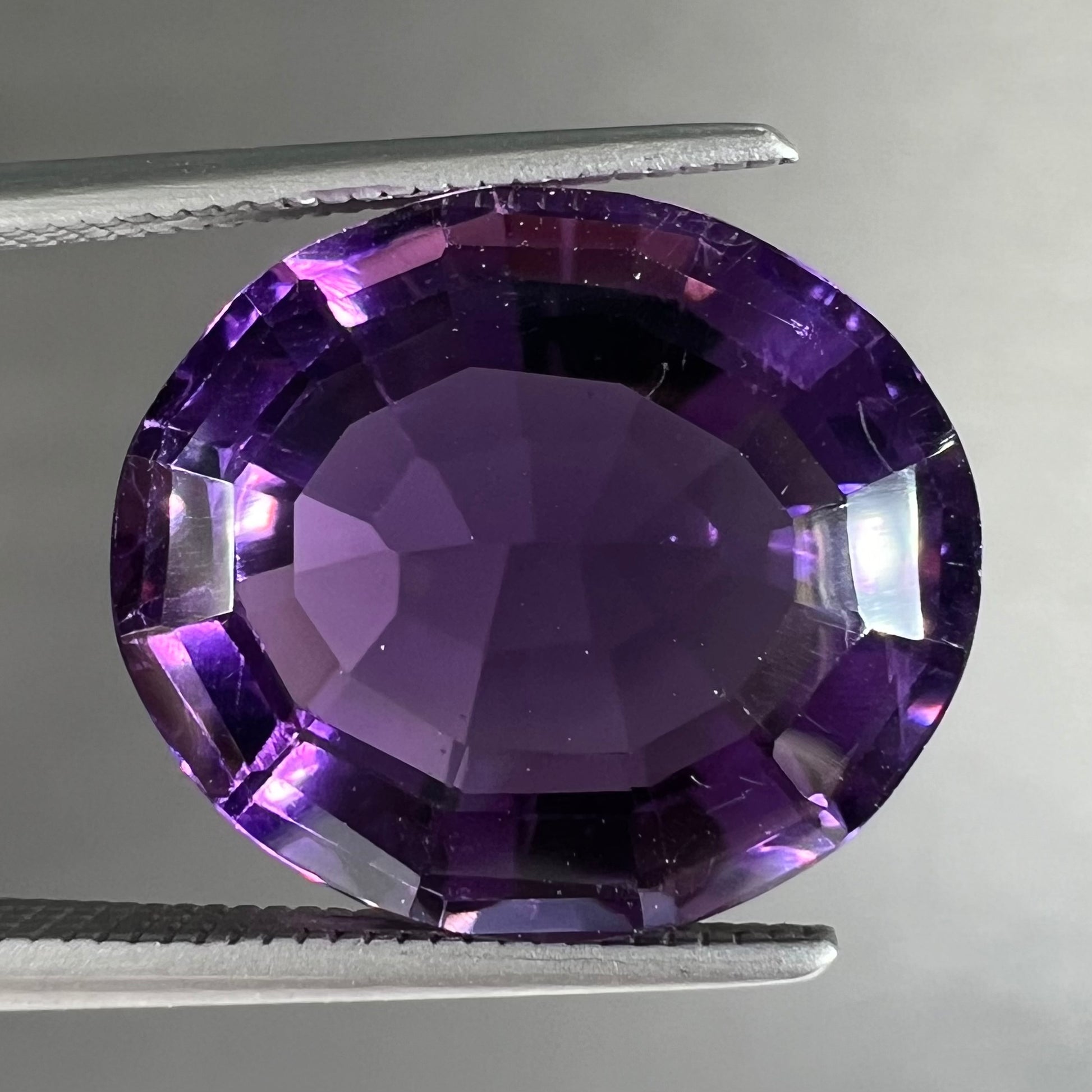 A loose, modified oval cut purple amethyst gemstone.