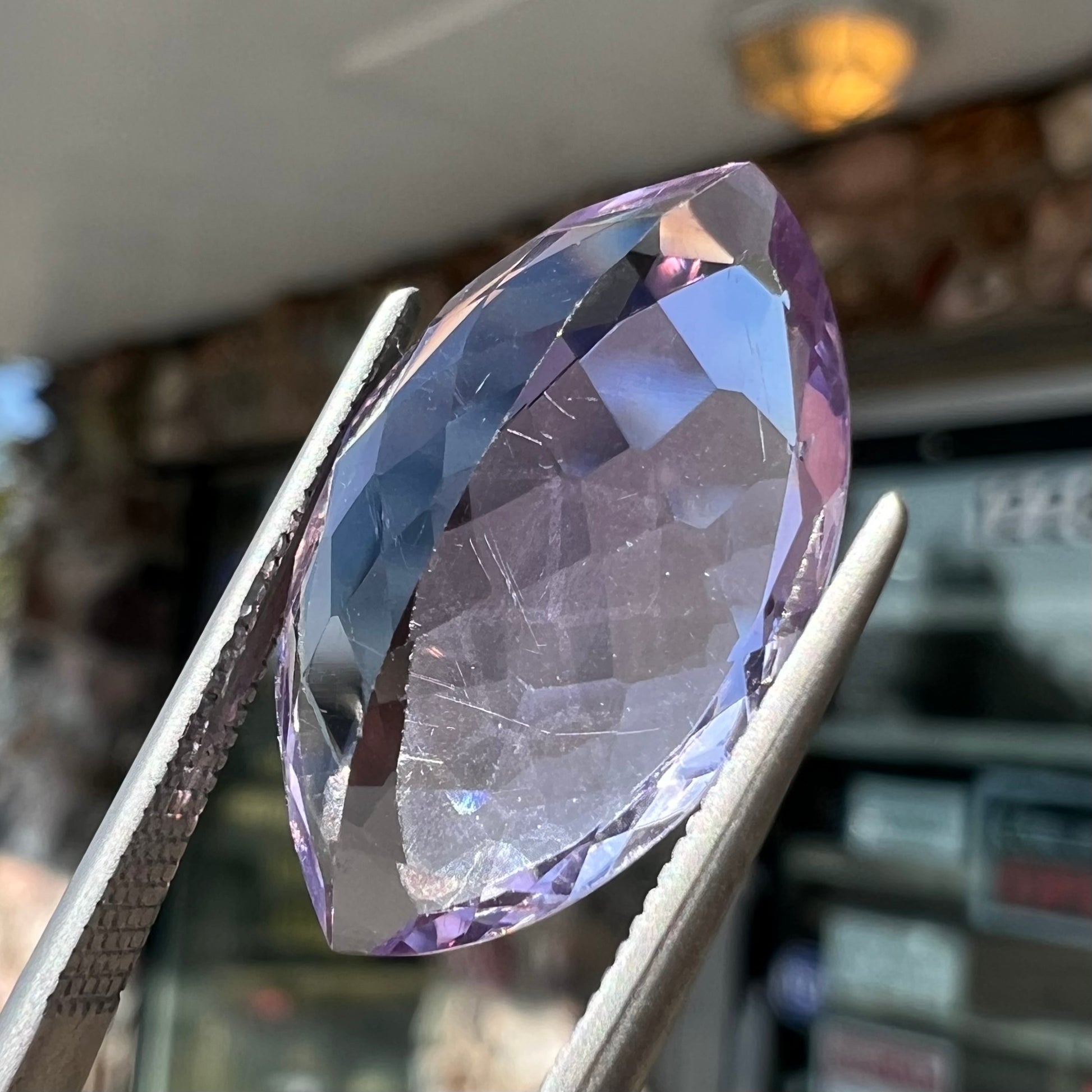 A loose marquise cut amethyst gemstone.  The stone is a light purple color and has scratches along the surface.