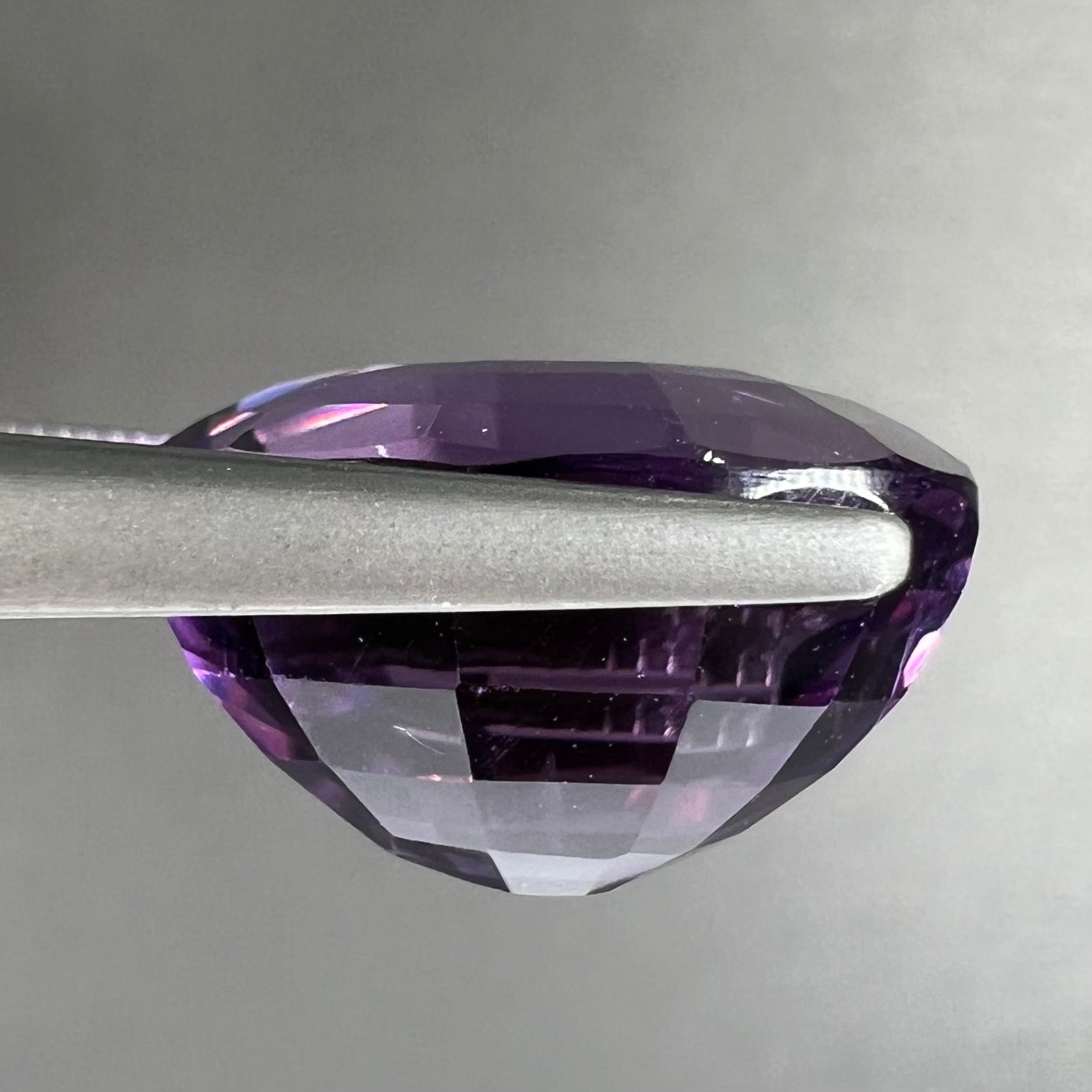 A loose, modified oval cut purple amethyst gemstone.