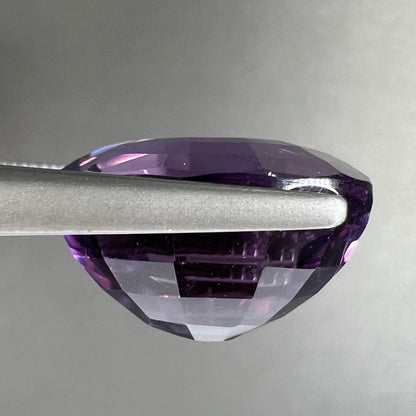A loose, modified oval cut purple amethyst gemstone.