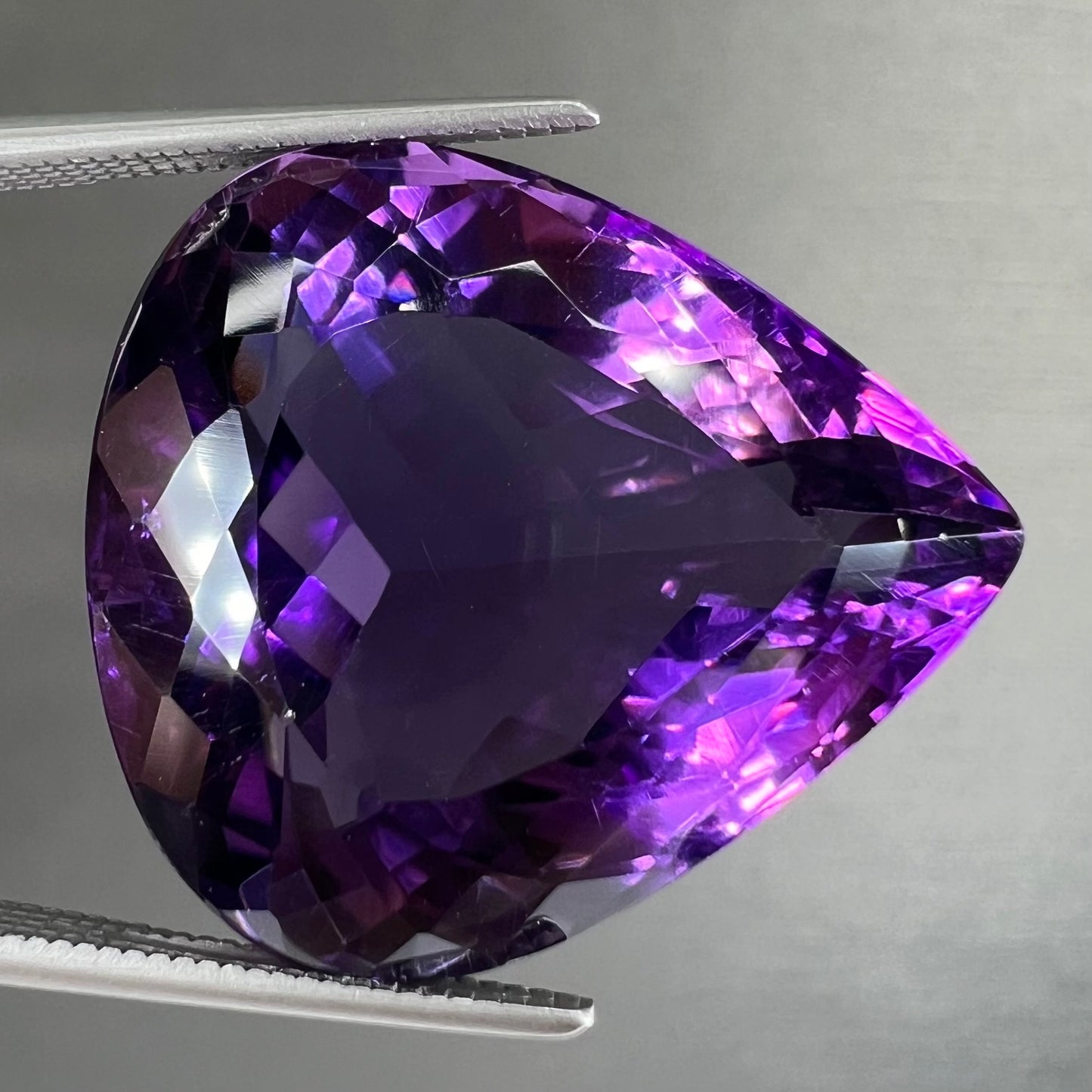 A large, pear shaped amethyst gemstone.  The stone is a dark purple color.