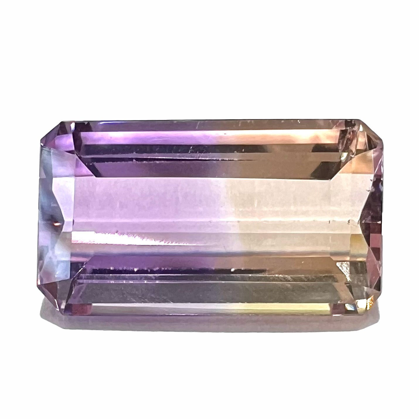 A loose, emerald cut ametrine stone.  The color fades from light purple to light yellow.