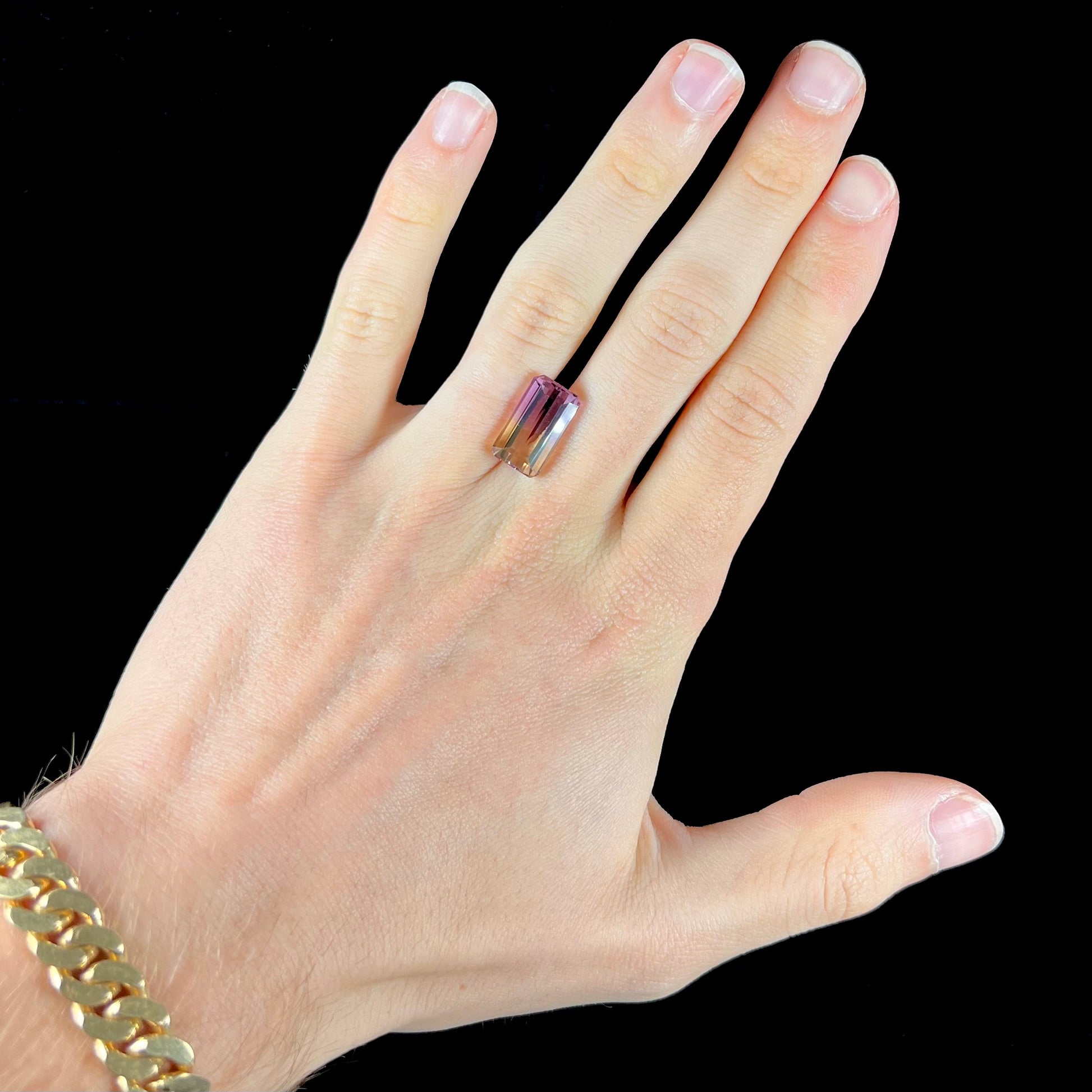 A loose, emerald cut ametrine stone.  The color fades from light purple to light yellow.