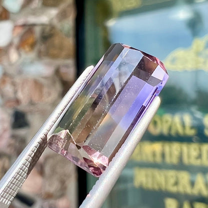 A loose, emerald cut ametrine stone.  The color fades from light purple to light yellow.