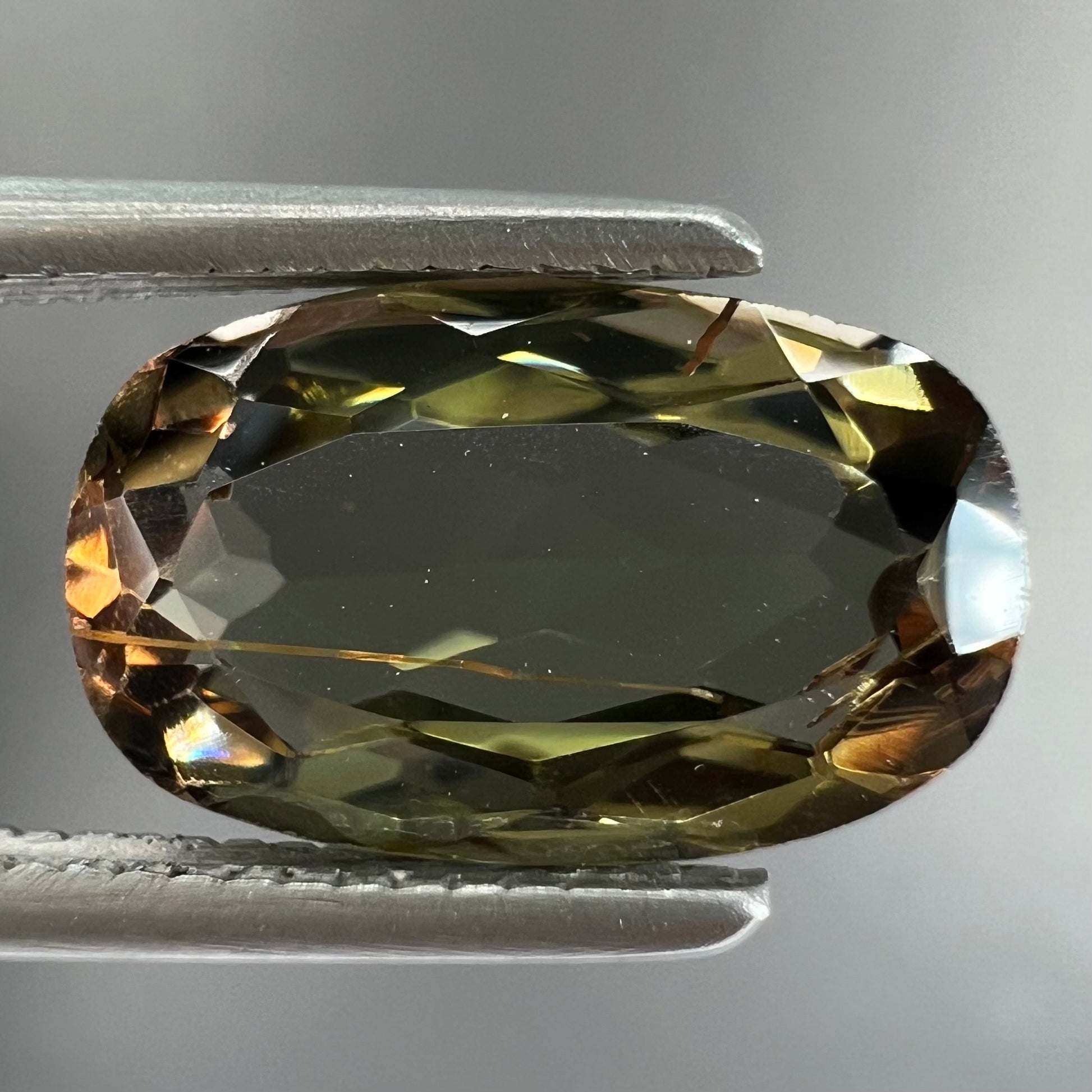A modified oval cut andalusite gemstone.  The stone has eye-visible rutile inclusions.