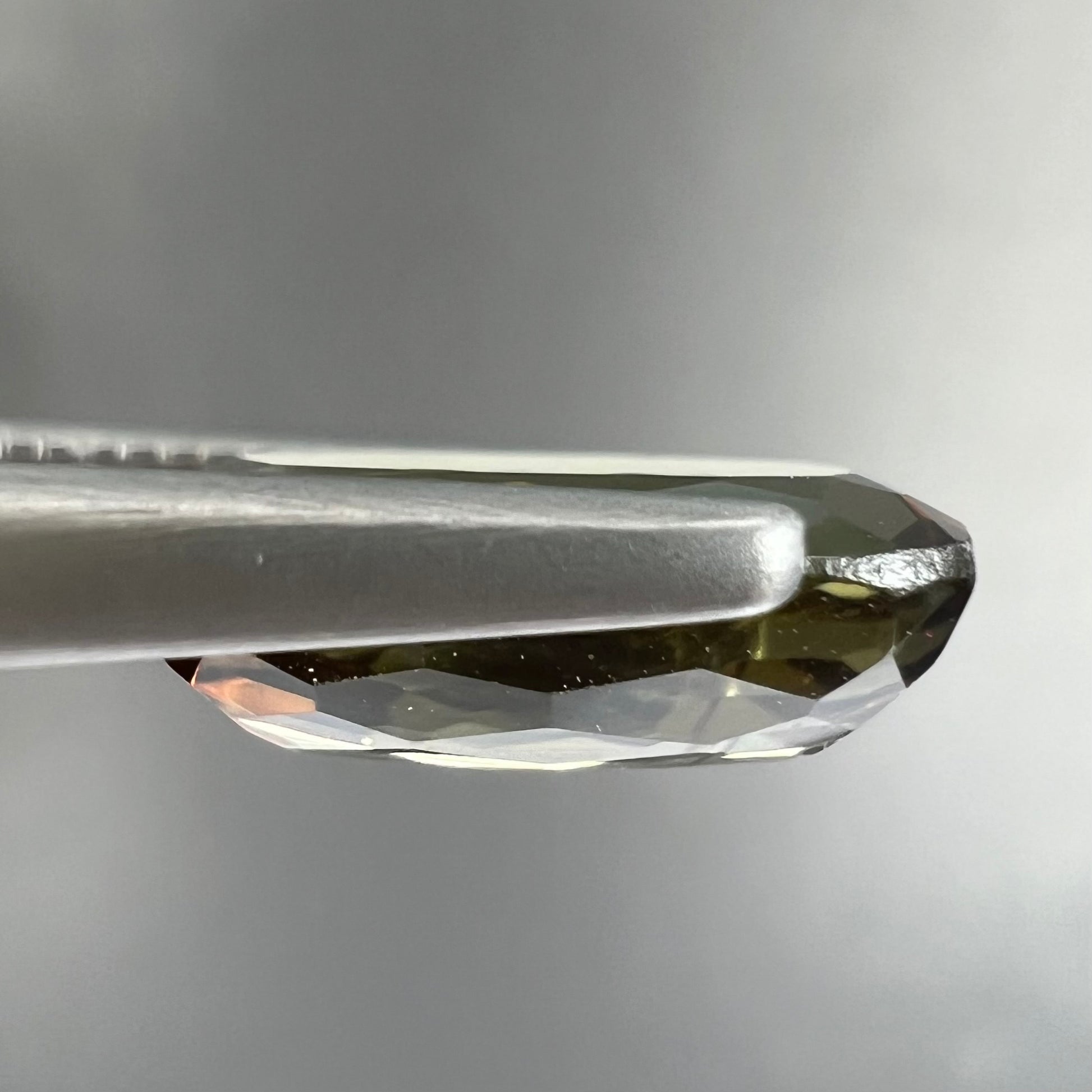 A modified oval cut andalusite gemstone.  The stone has eye-visible rutile inclusions.