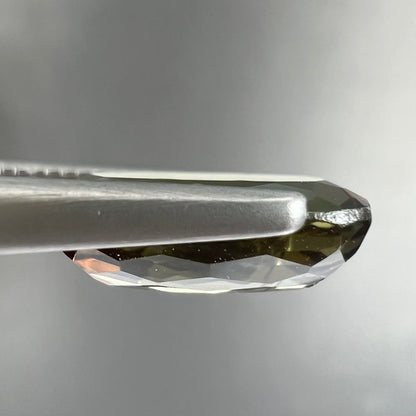 A modified oval cut andalusite gemstone.  The stone has eye-visible rutile inclusions.
