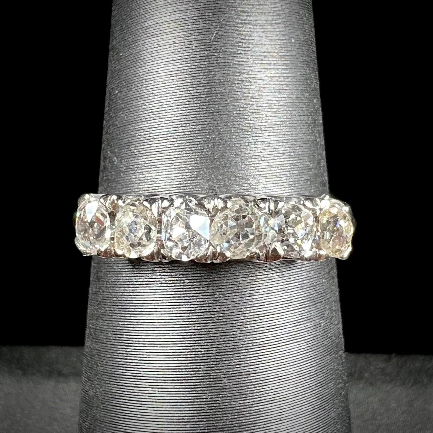 An antique white gold diamond wedding band set with six old mine cut natural diamonds.