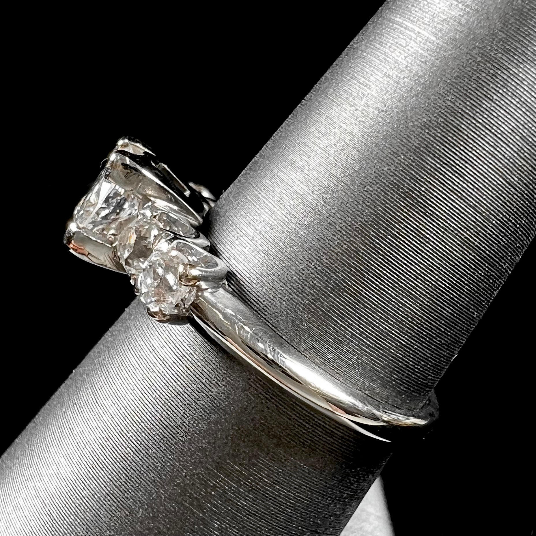 A ladies' 1800's antique white gold diamond ring.  The center stone is an Early American Cut diamond, and the accent stones are Old Mine Cut diamonds.