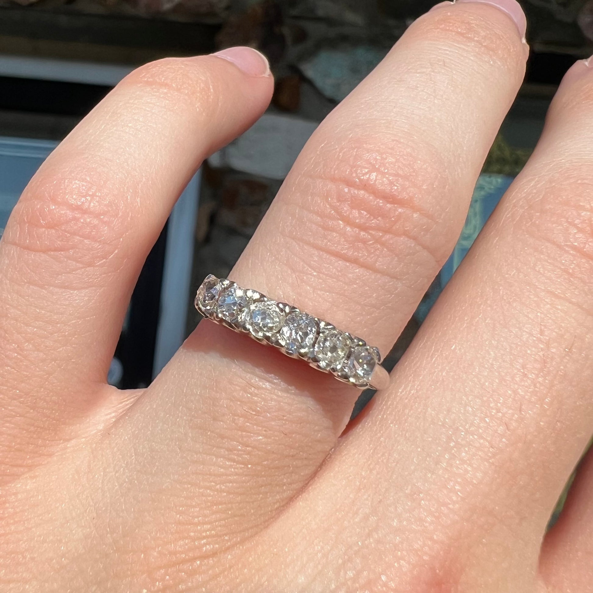 An antique white gold diamond wedding band set with six old mine cut natural diamonds.