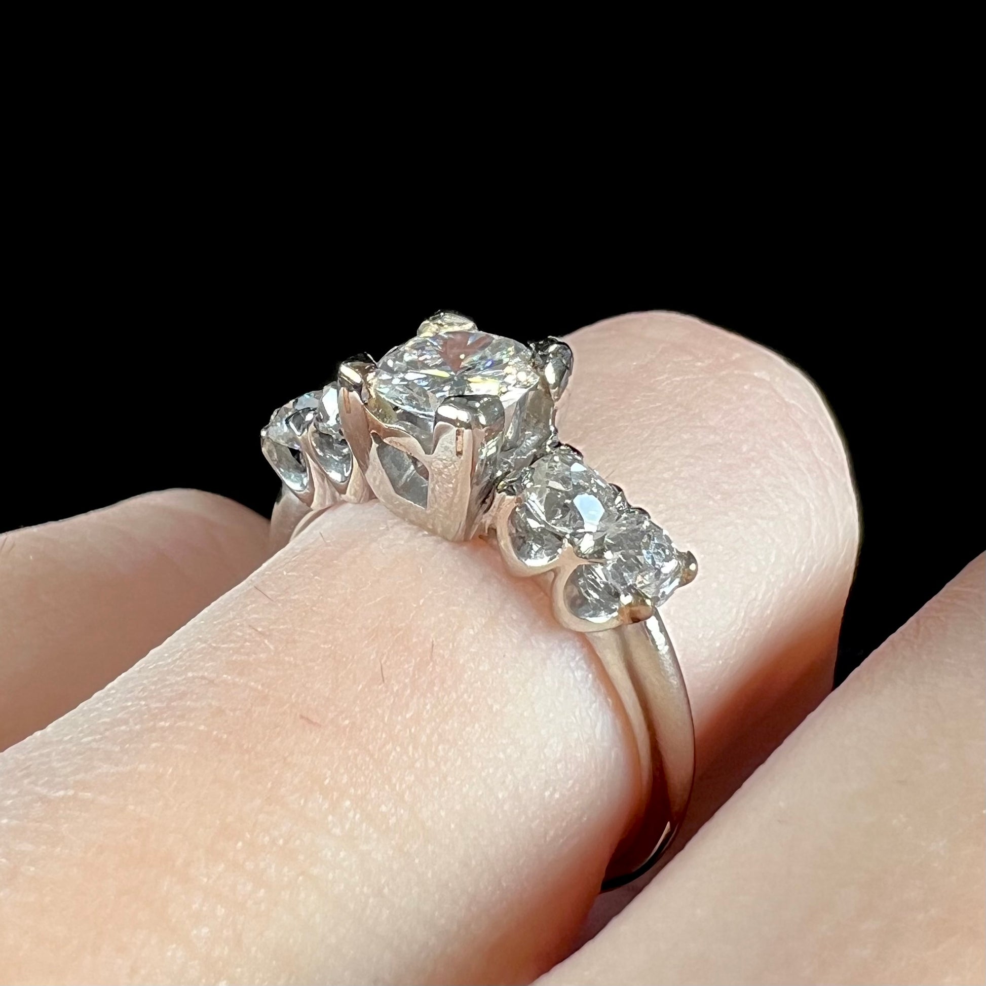A ladies' 1800's antique white gold diamond ring.  The center stone is an Early American Cut diamond, and the accent stones are Old Mine Cut diamonds.