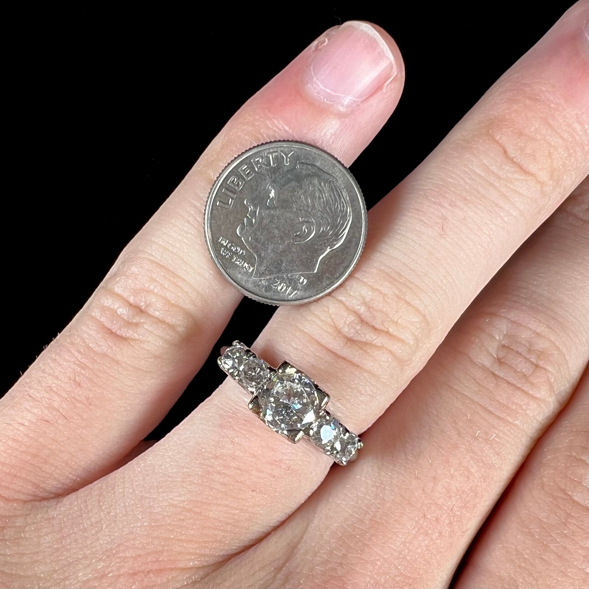 A ladies' 1800's antique white gold diamond ring.  The center stone is an Early American Cut diamond, and the accent stones are Old Mine Cut diamonds.