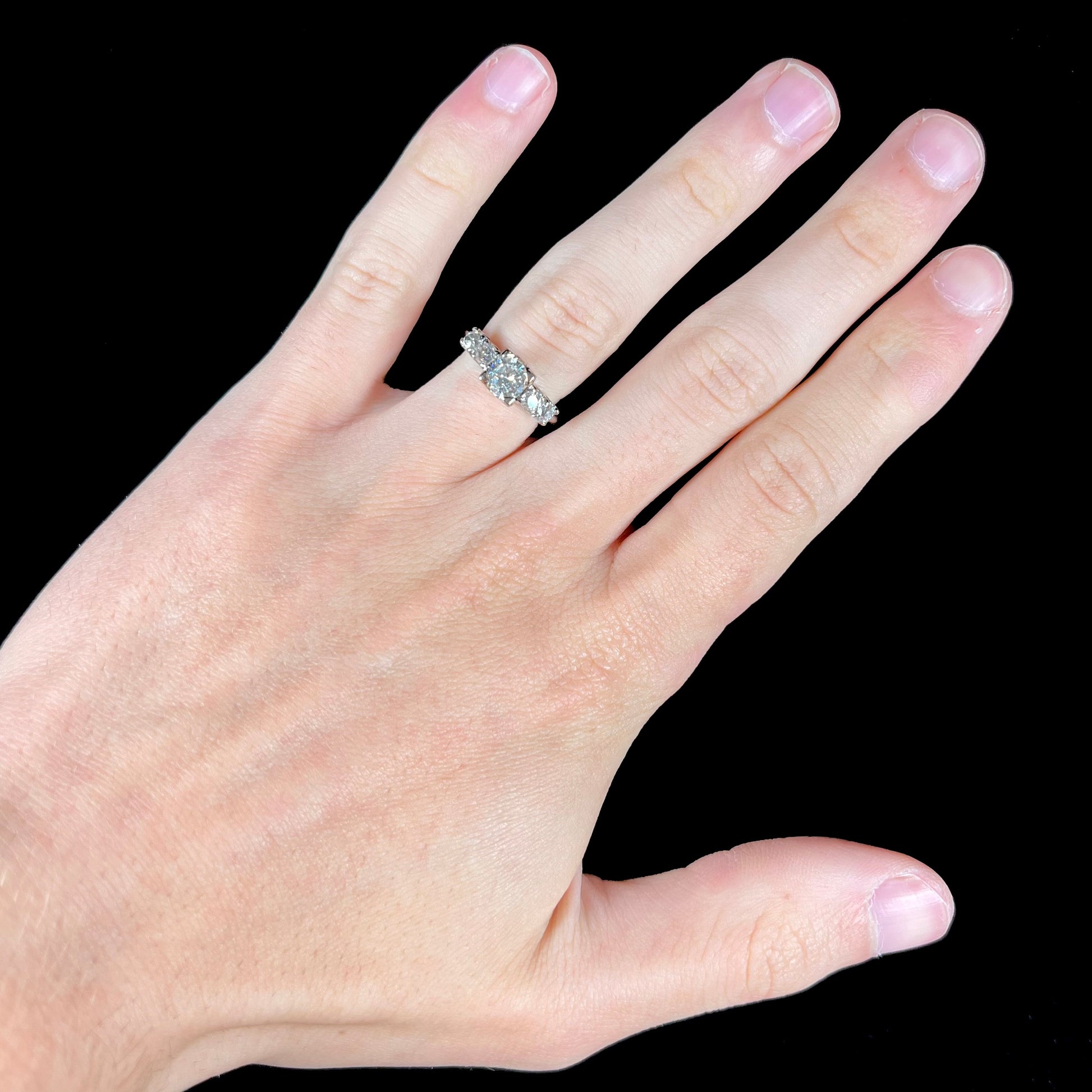 A ladies' 1800's antique white gold diamond ring.  The center stone is an Early American Cut diamond, and the accent stones are Old Mine Cut diamonds.