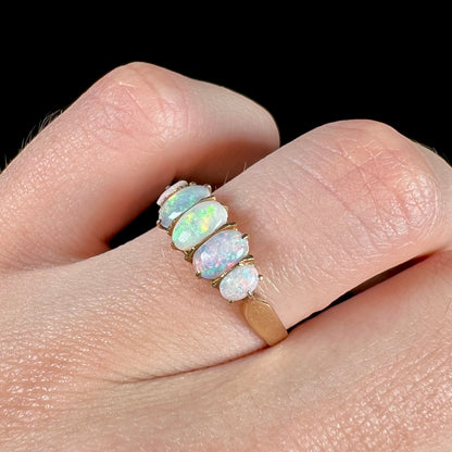 A ladies' Edwardian style 18 karat yellow gold ring set with five natural oval cut opal stones.