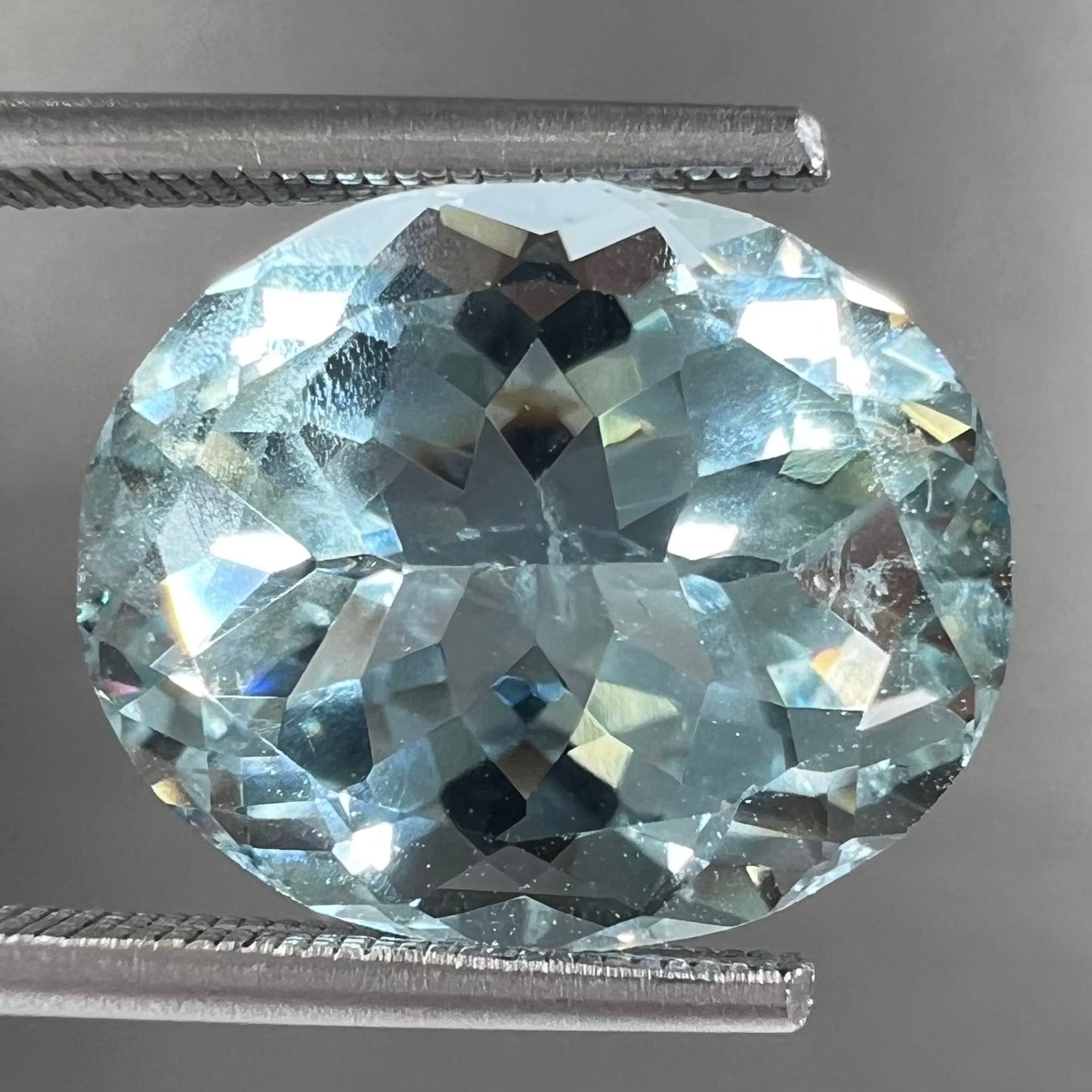 A loose, faceted oval cut aquamarine gemstone from Brazil.  The stone is greenish blue color.