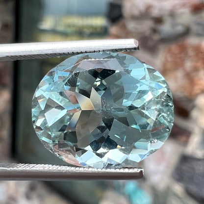 A loose, faceted oval cut aquamarine gemstone from Brazil.  The stone is greenish blue color.
