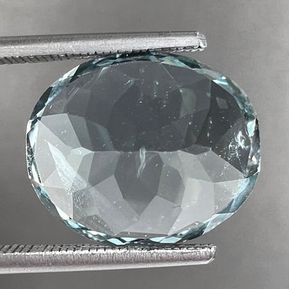 A loose, faceted oval cut aquamarine gemstone from Brazil.  The stone is greenish blue color.