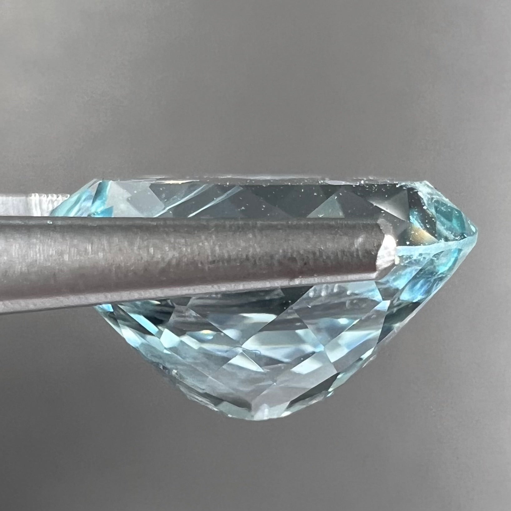 A loose, faceted oval cut aquamarine gemstone from Brazil.  The stone is greenish blue color.