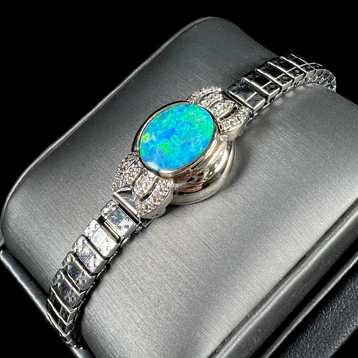 A ladies' art deco style white gold and stainless steel bracelet set with a natural black opal doublet and diamonds.