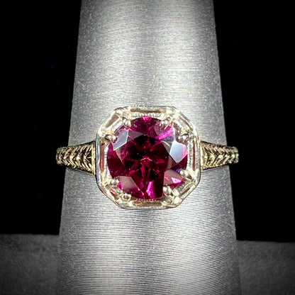 A ladies' yellow gold Art Deco style solitaire ring set with a purple rhodolite garnet gemstone.