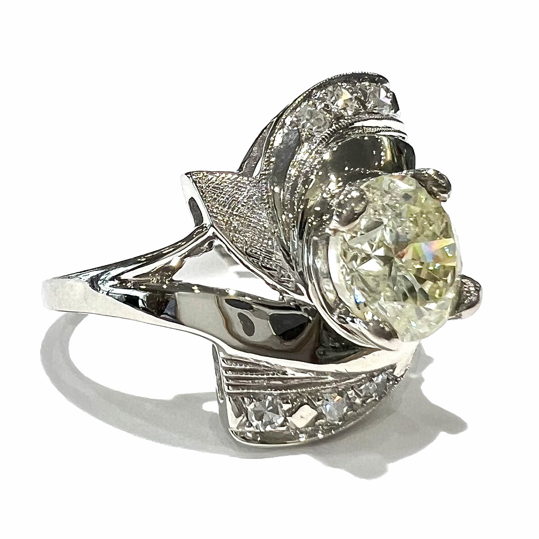 A vintage, Art Nouveau style diamond engagment ring.  The ring is white gold with a yellowish, M colored, 1.24 carat diamond.