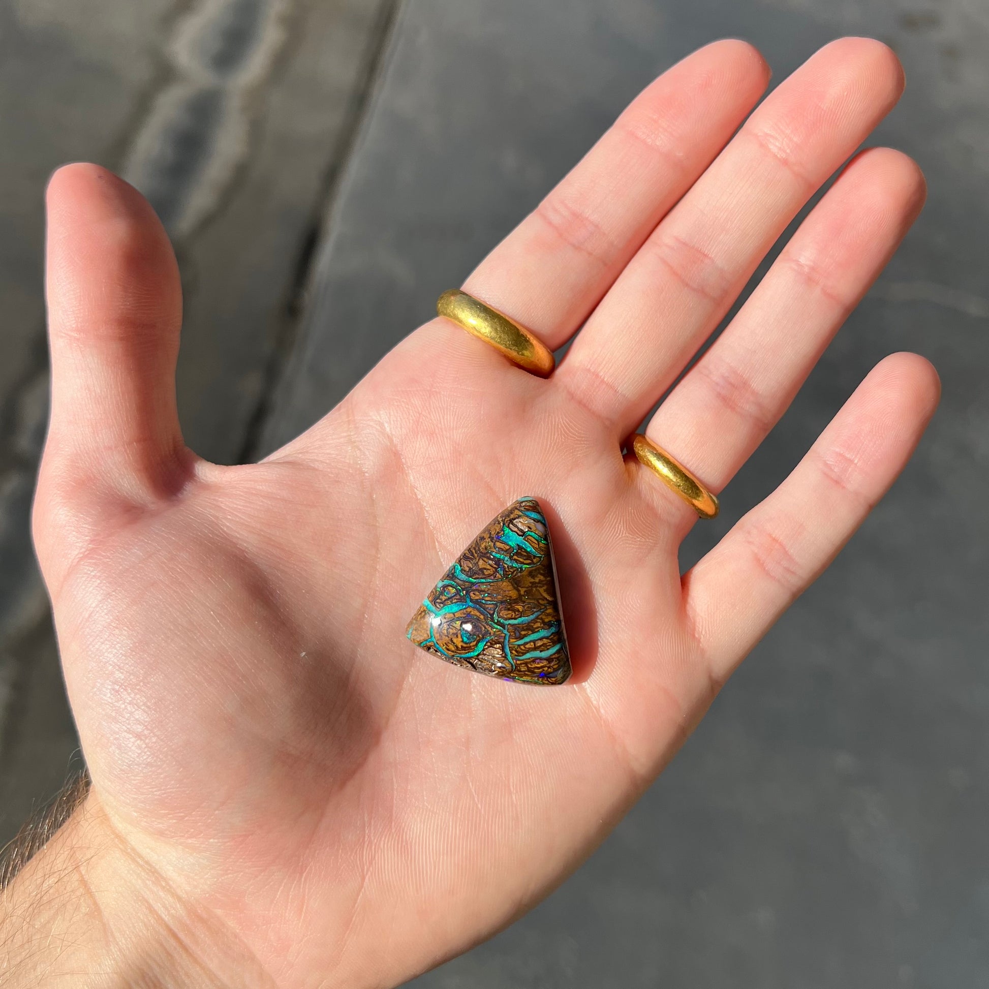 A triangle shaped Koroit boulder opal.  The stone has blue veins of opal running through it.
