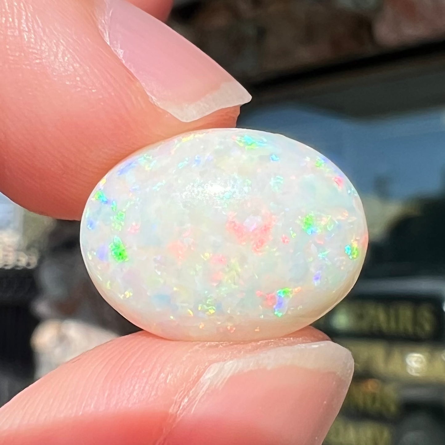 An oval cabochon cut white opal.  The opal has an eye-visible natural fissure inclusion.