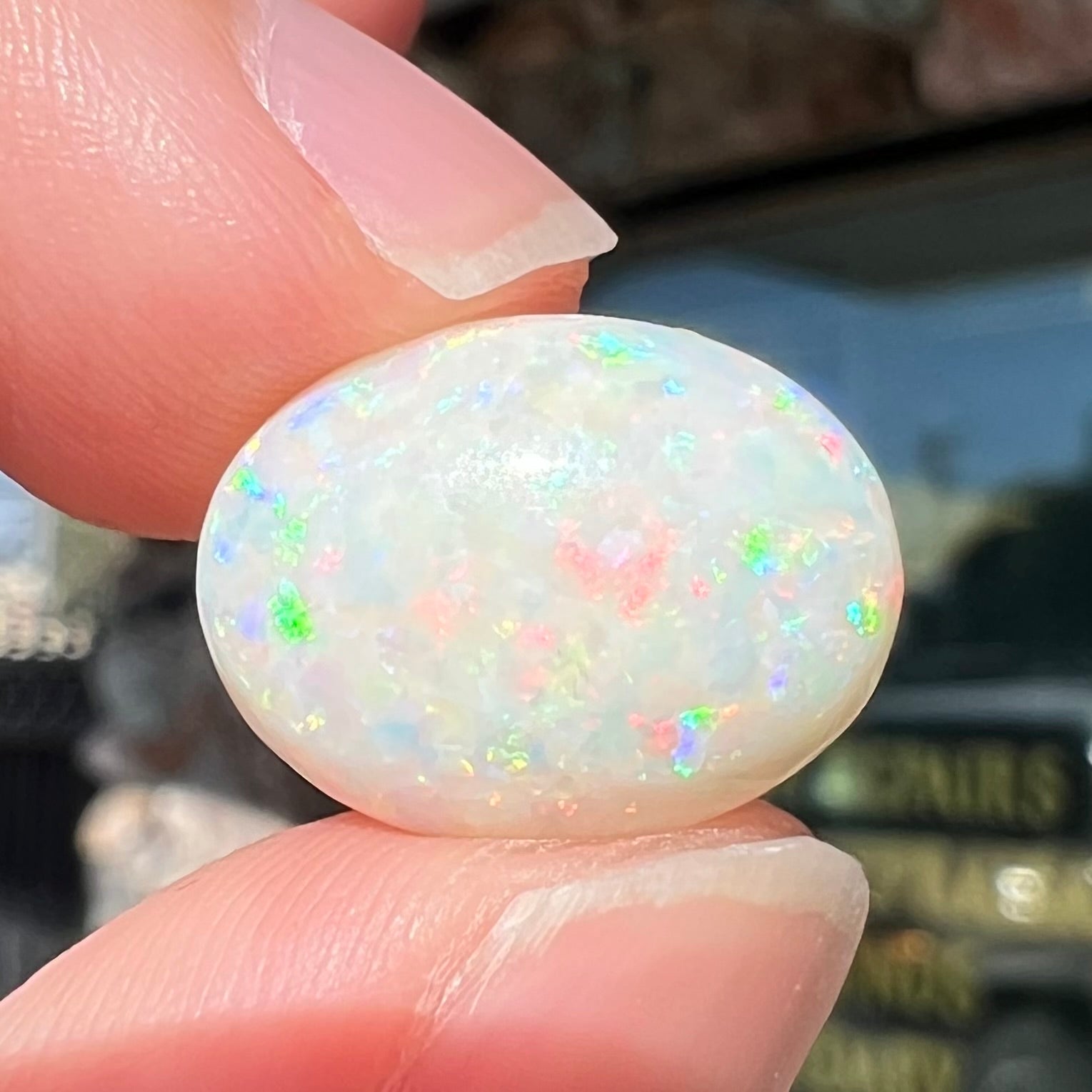An oval cabochon cut white opal.  The opal has an eye-visible natural fissure inclusion.