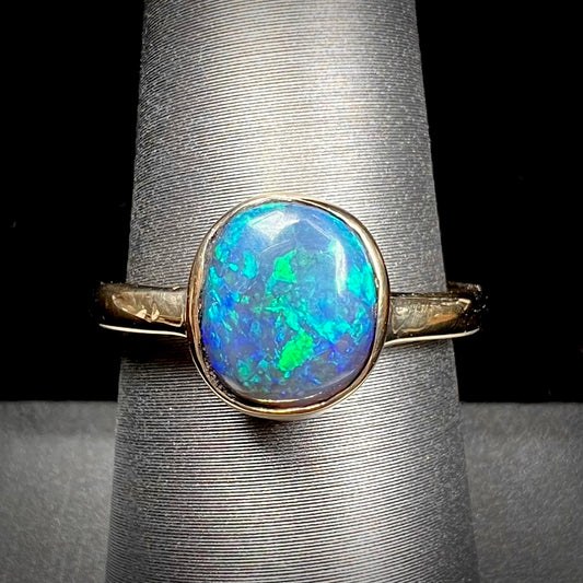 A ladies' natural black crystal opal solitaire ring handmade in 14 karat yellow gold.