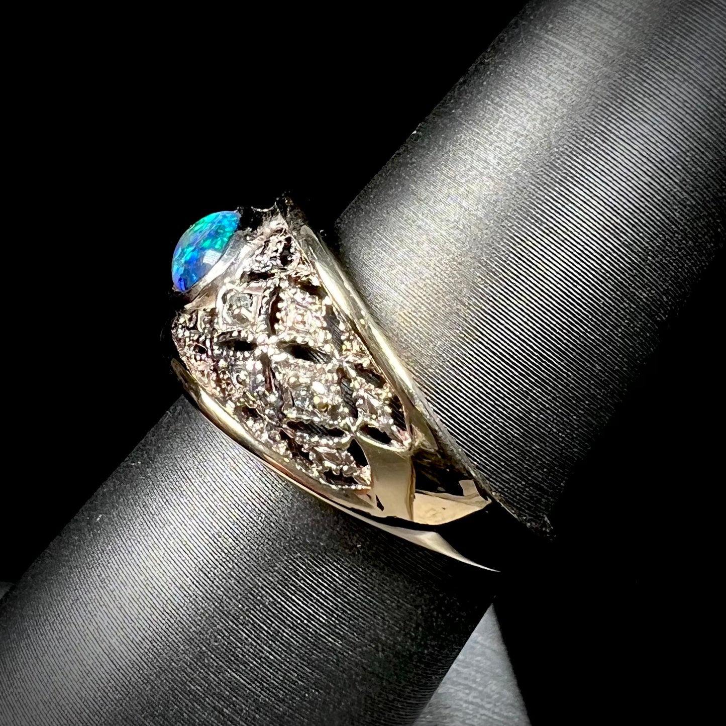 A ladies' yellow gold filigree style ring set with a natural black opal and diamond accents.