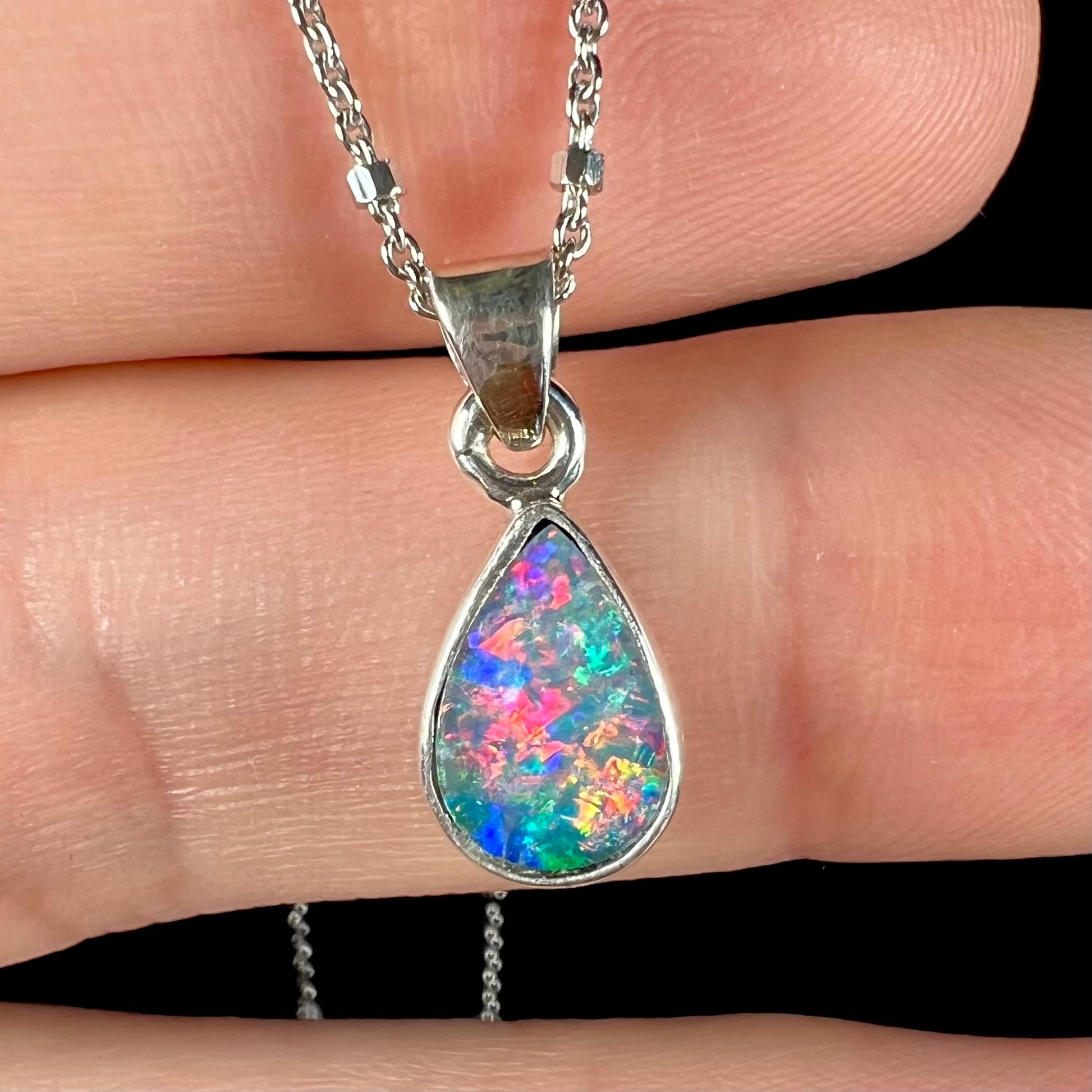 A pear shaped black opal necklace set in sterling silver.  The opal vividly flashes every color of the rainbow.