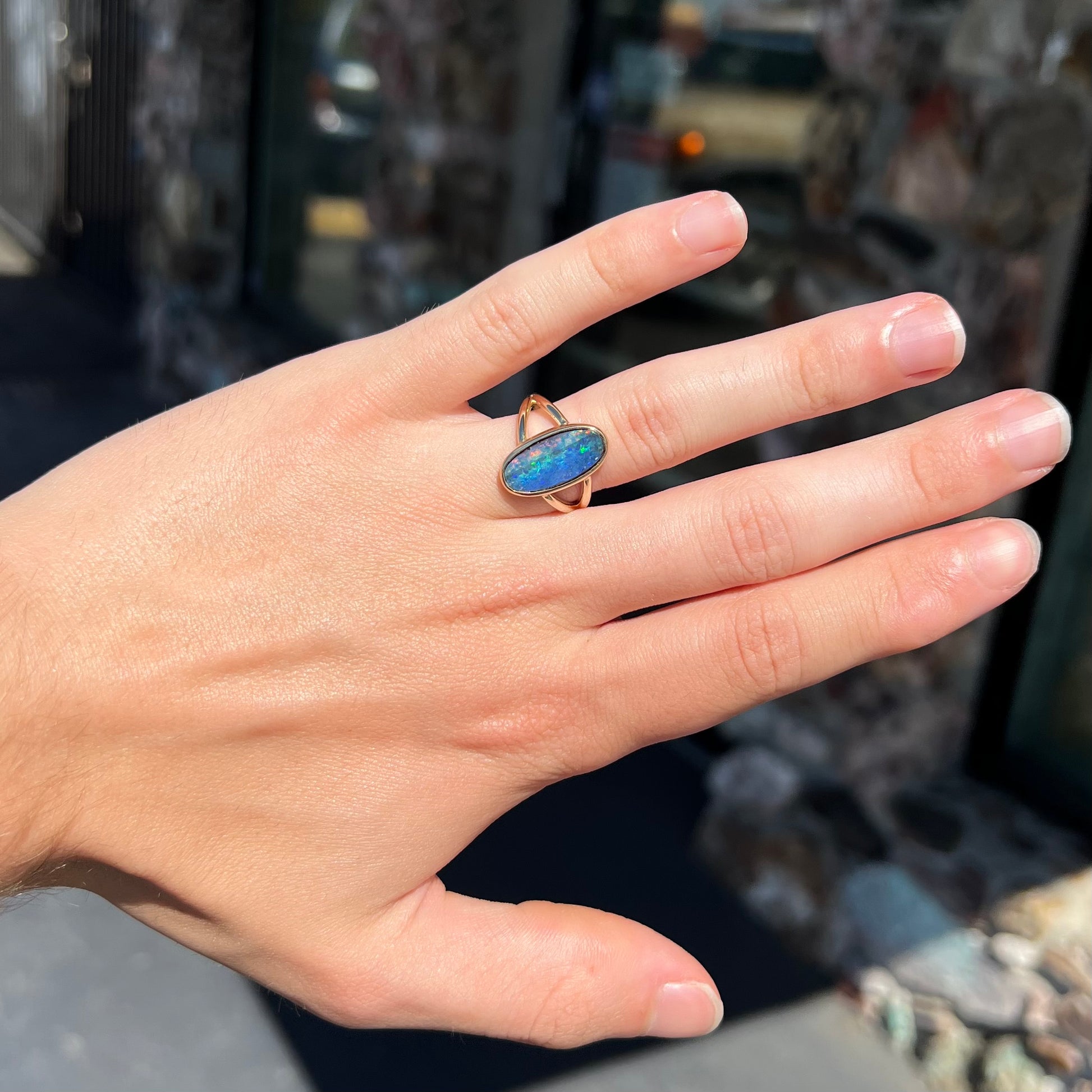 A ladies' yellow gold split shank solitaire ring set with a natural Australian black boulder opal.