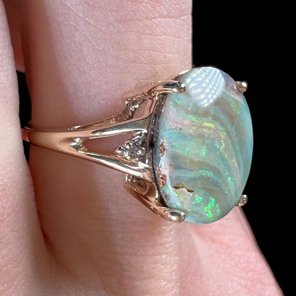 A ladies' Australian boulder opal ring set in yellow gold with diamond accents.  The opal shimmers green and pink and has fissure inclusions.