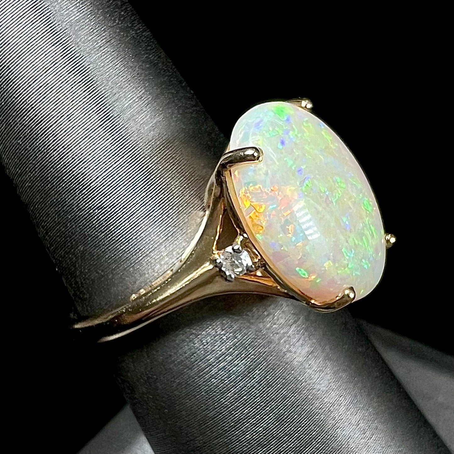 A ladies' yellow gold ring set with two diamonds and an oval cut natural opal stone.