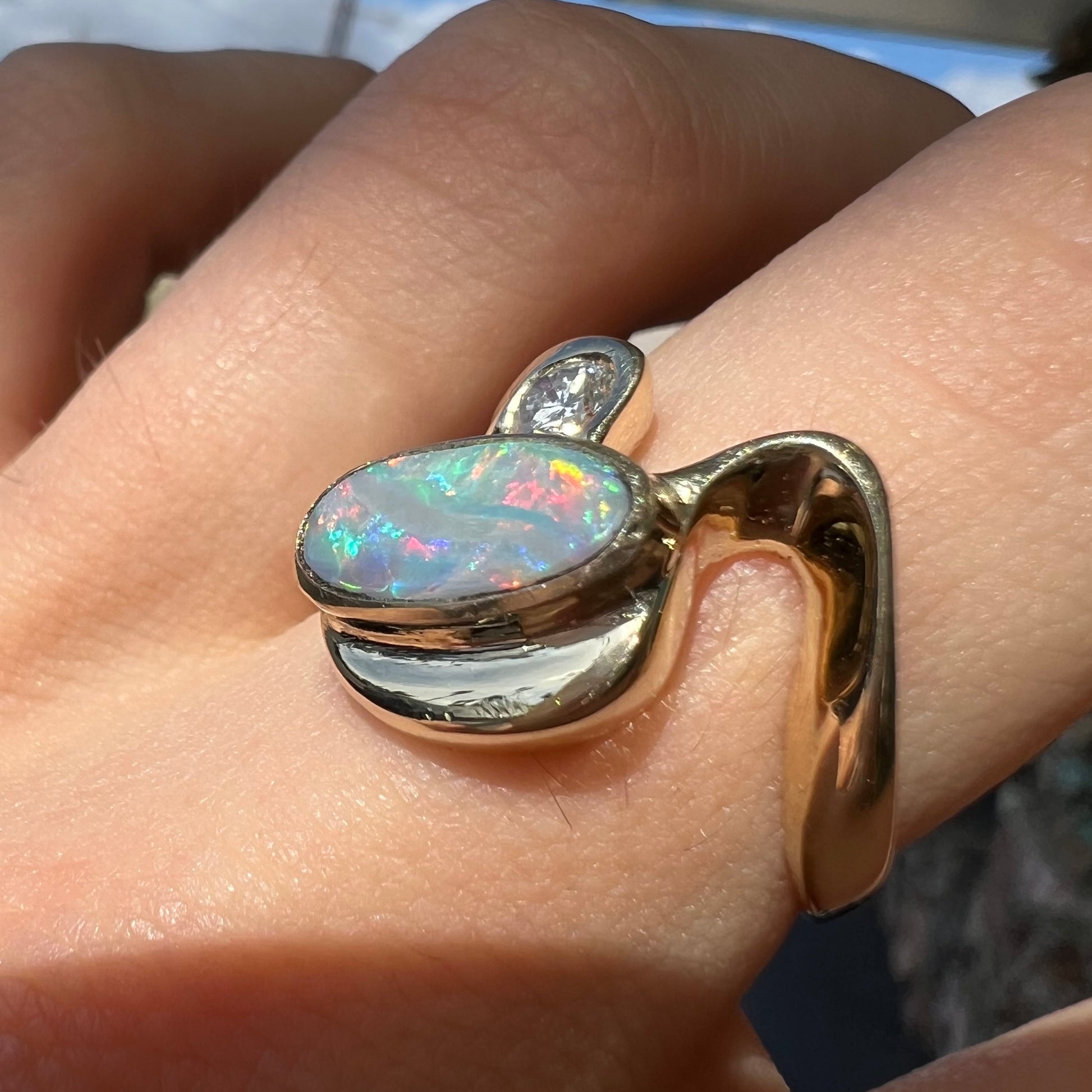 A ladies' yellow gold, bezel set ring mounted with a natural 1.15 carat black opal and round diamond.