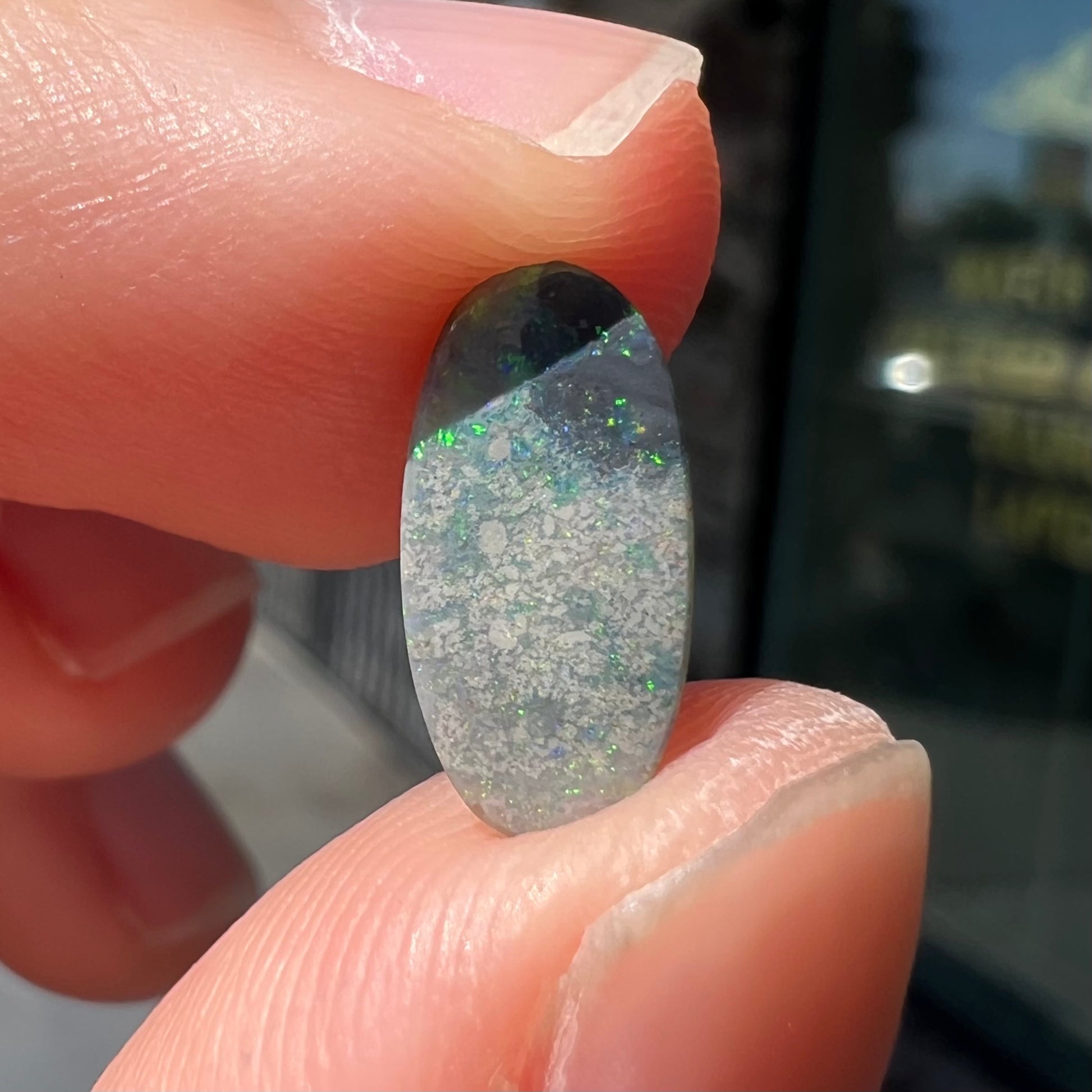 A loose, oval cabochon cut opal gemstone from Lightning Ridge, Australia.  The opal shines red and orange colors.