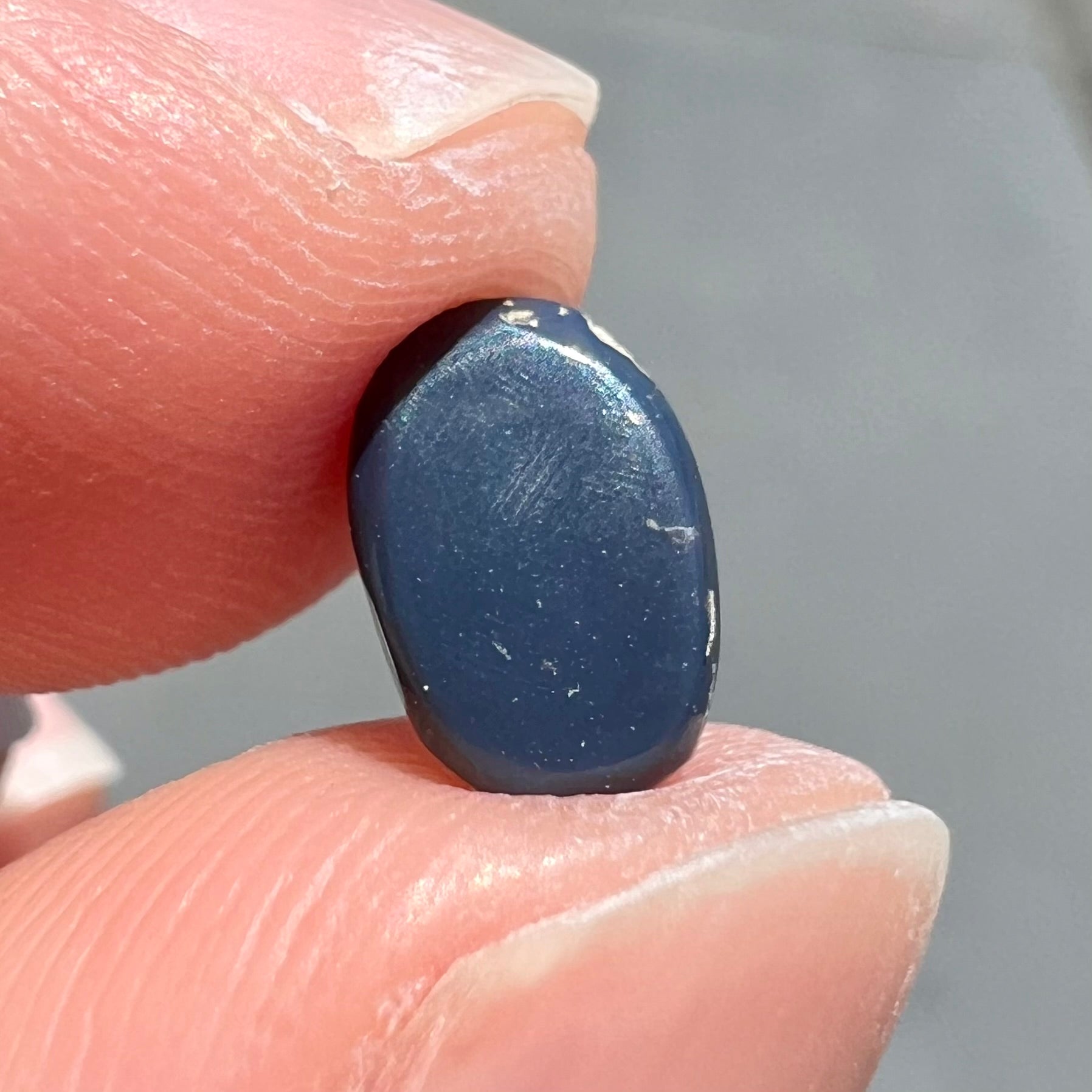 A loose black opal from Lightning Ridge, Australia.  The opal displays a blue cat's eye pattern.