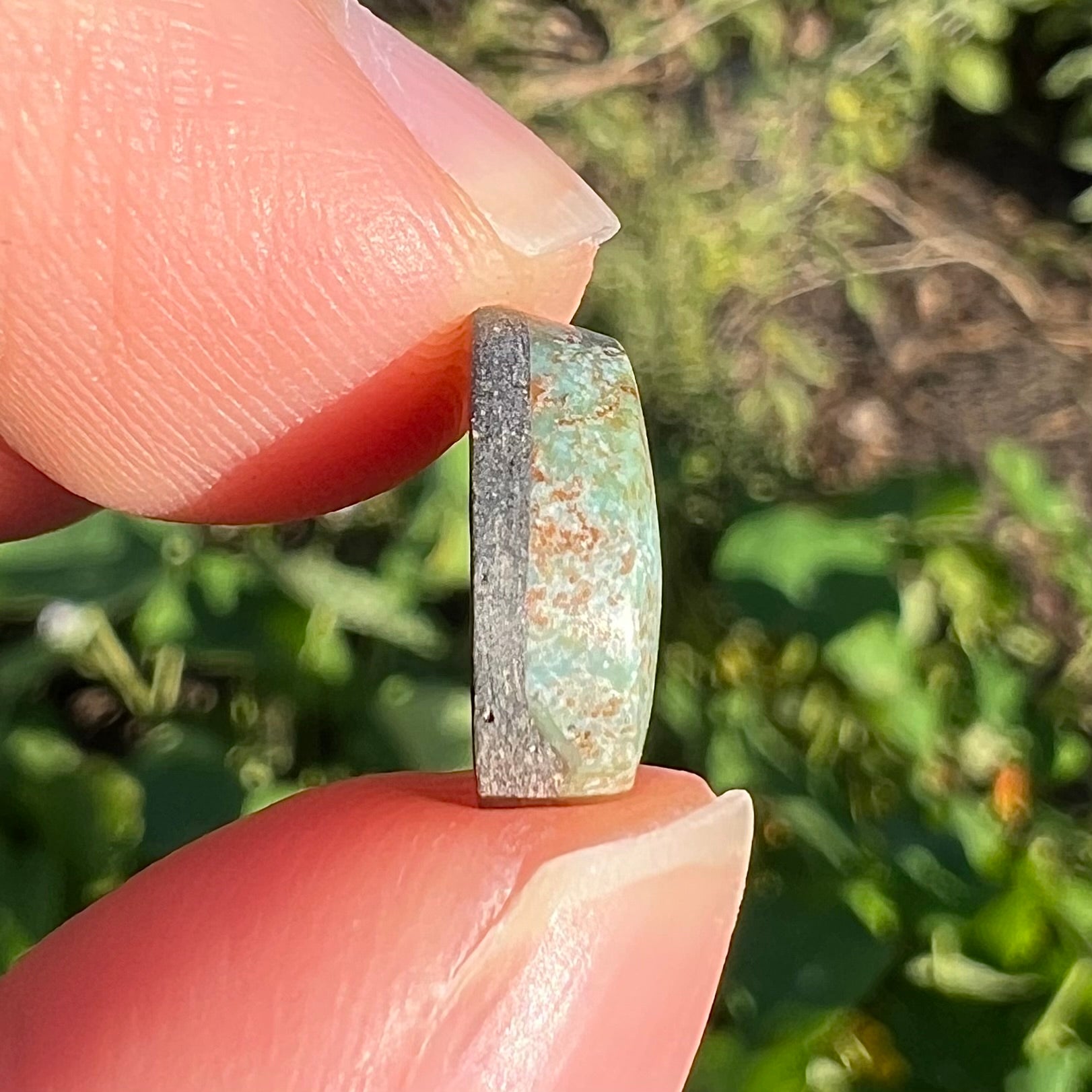 A loose, off-round cabochon cut turquoise stone.  The stone is light blue with a red webbed matrix.