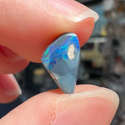 A 1.63 carat loose black opal stone from Lightning Ridge, Australia.  The opal is a freeform shape.