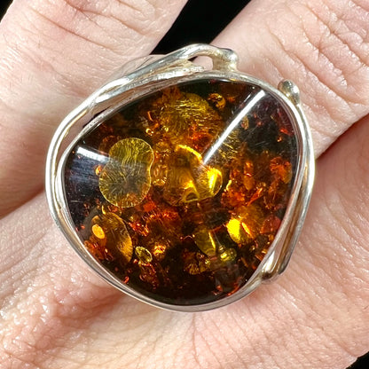 Unisex sterling silver ring set with a large sun-spangled Baltic amber gemstone.
