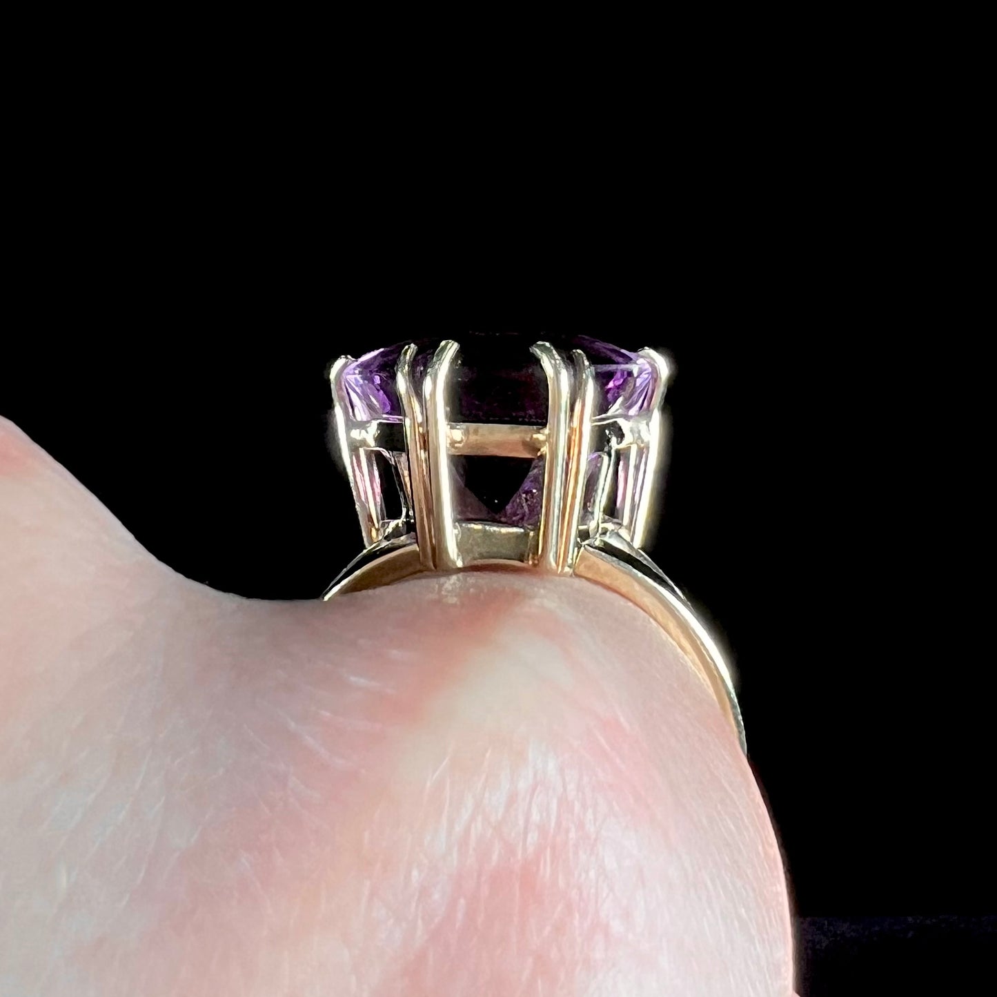 A ladies' yellow gold cocktail ring set with a shield cut purple amethyst gemstone.