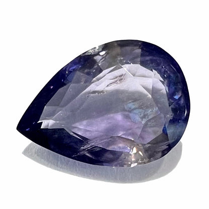 A loose, pear shaped bicolor iolite gemstone.  The stone shows violite purple and silver colors.  The iolite weighs 5.05 carats.
