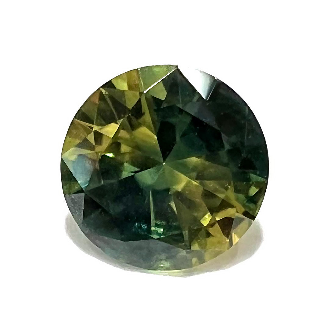 A loose, round brilliant cut Australian parti sapphire.  The stone shows colors of yellow, green, and blue.