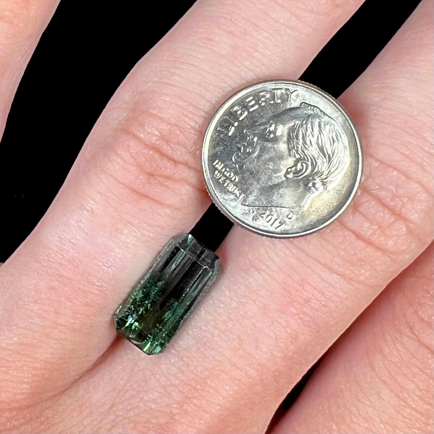 A loose, emerald cut bicolor tourmaline stone.  The colors blend from green to blue-green to sttel blue.