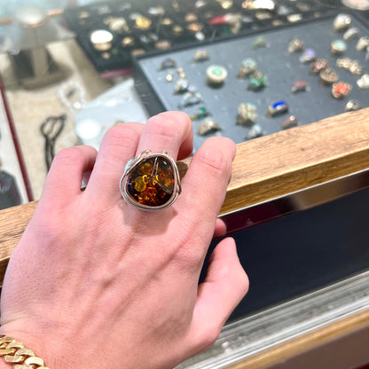 Unisex sterling silver ring set with a large sun-spangled Baltic amber gemstone.