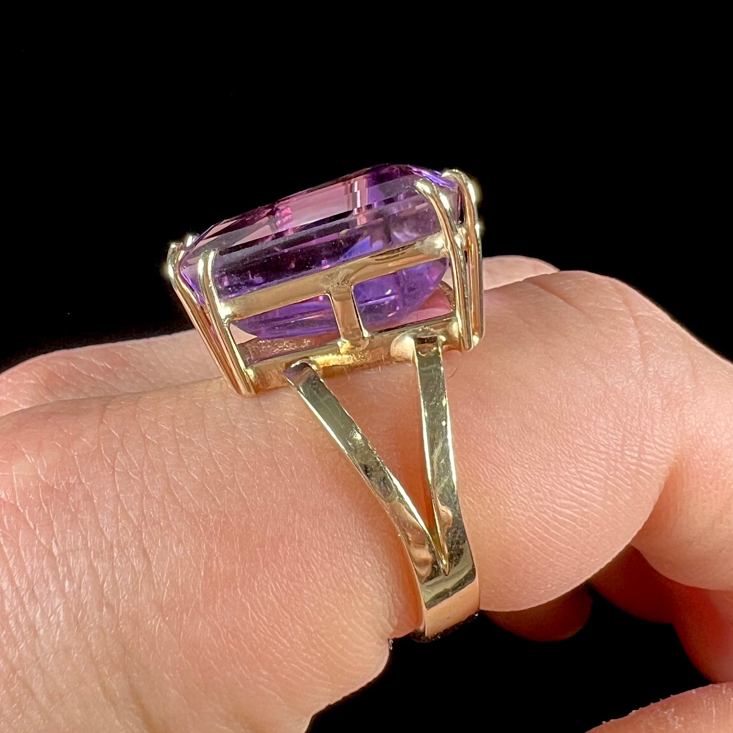 A ladies' yellow gold cocktail ring set with a shield cut purple amethyst gemstone.