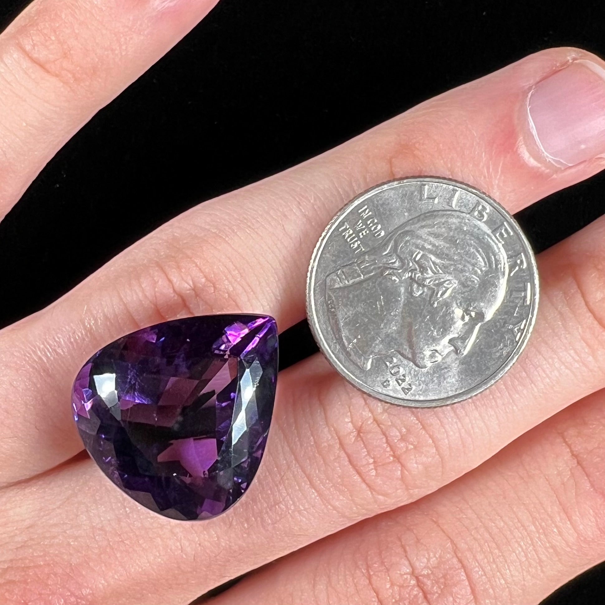 A large, pear shaped amethyst gemstone.  The stone is a dark purple color.