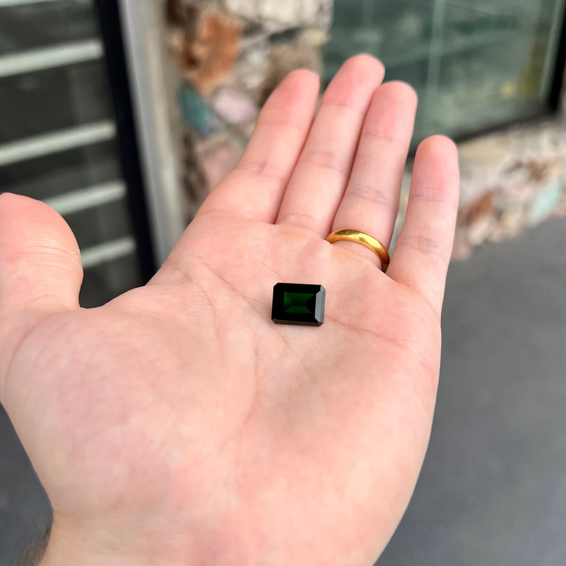 A large, emerald cut chrome diopside gemstone.  The gem is dark green color.